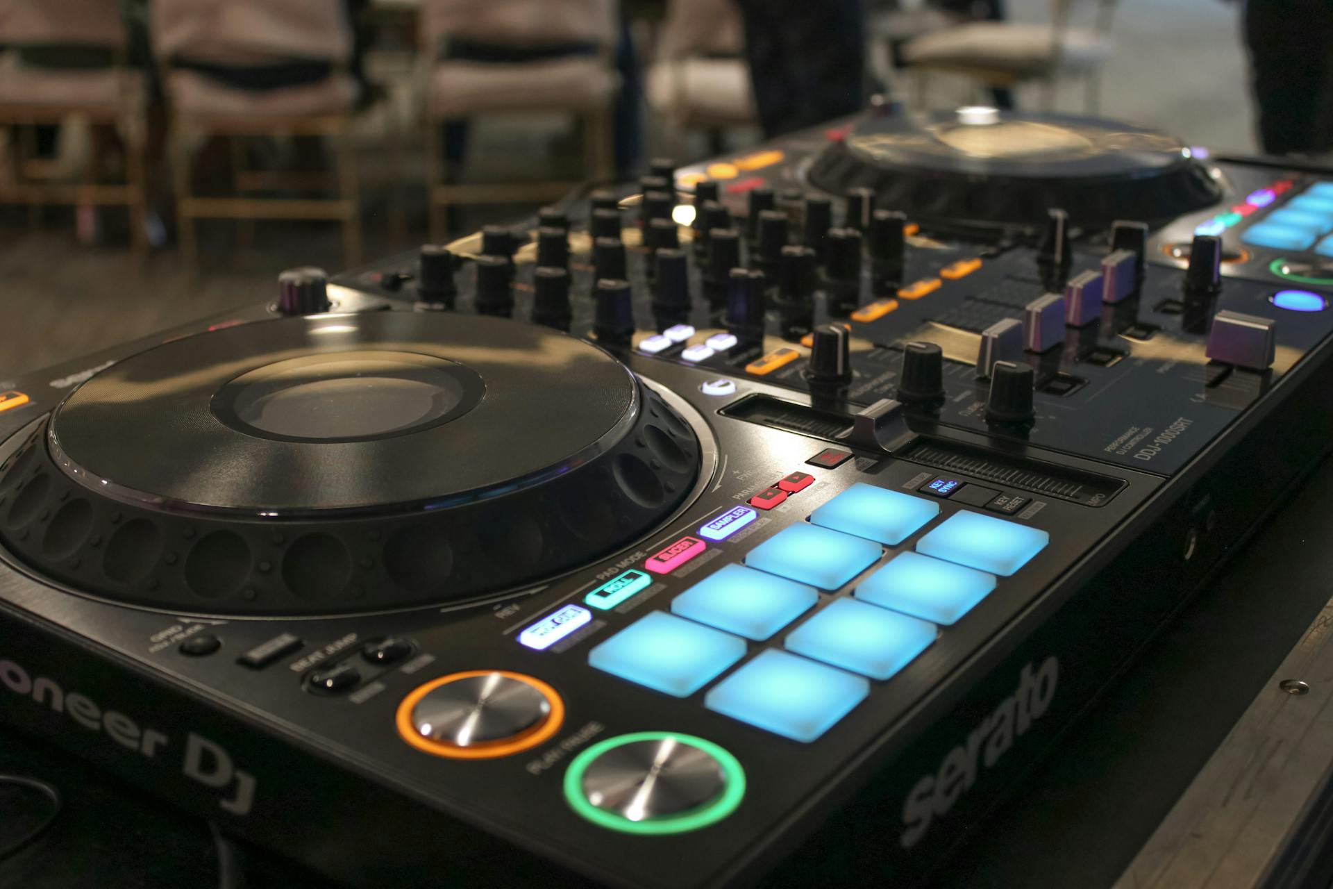 Close-up of a Pioneer DJ mixer console with illuminated buttons and dials in a studio setting.