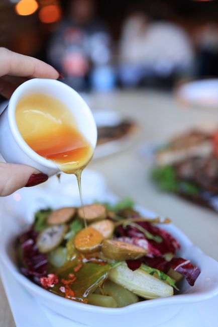 A small bowl of golden honey mustard sauce with visible flecks of whole grain mustard, a whisk resting against the rim.
