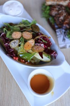 Delicious mixed green salad with nuts and honey dressing in an elegant dish.