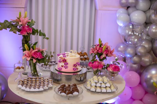 Birthday Cake and Sweets on a Table Decorated with Flowers and Balloons 