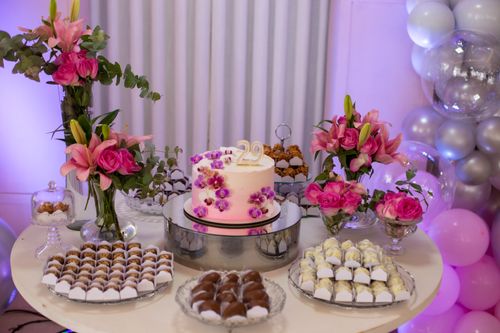Free A beautifully decorated birthday cake with pink flowers and a 29 topper surrounded by sweets and balloons. Stock Photo