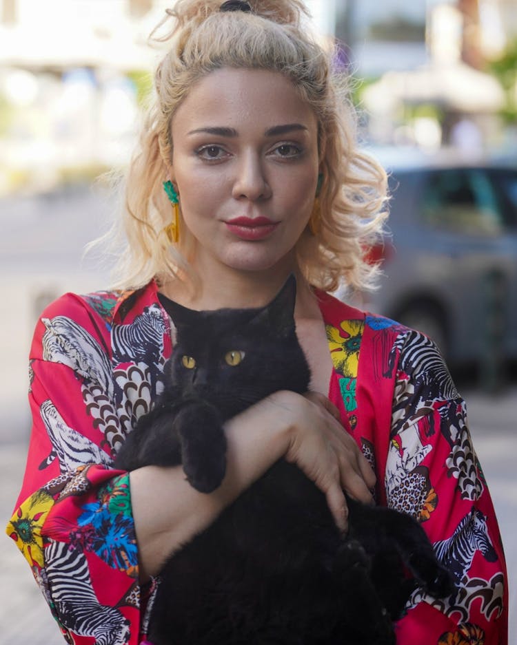 A Woman In Printed Shirt Carrying Her Cat