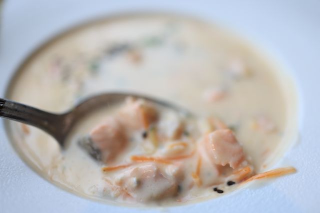 Close-up of creamy salmon soup with vegetables, showcasing a delicious and healthy meal.