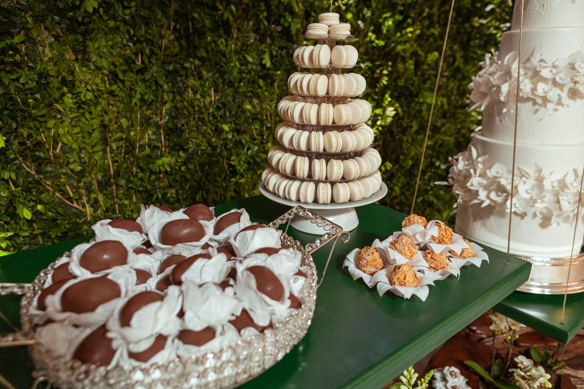 A sophisticated dessert display featuring a macaron tower, truffles, and a tiered wedding cake.