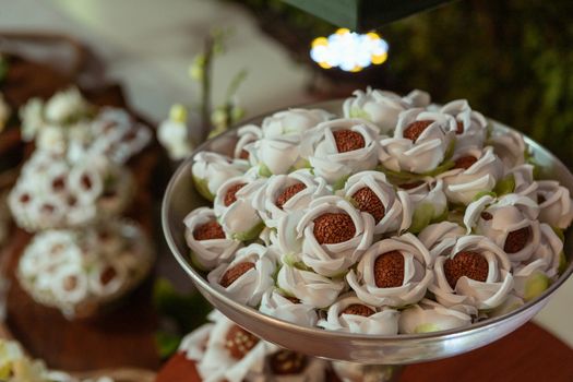 Close-up of a dessert tray with chocolate truffles in decorative floral wrappers.