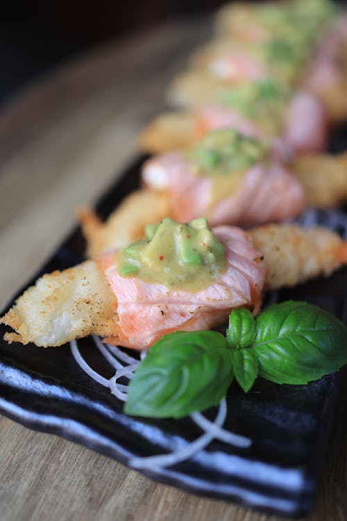 Deep Fried Fish Topped with Salmon and Garnish Served on Black Plate