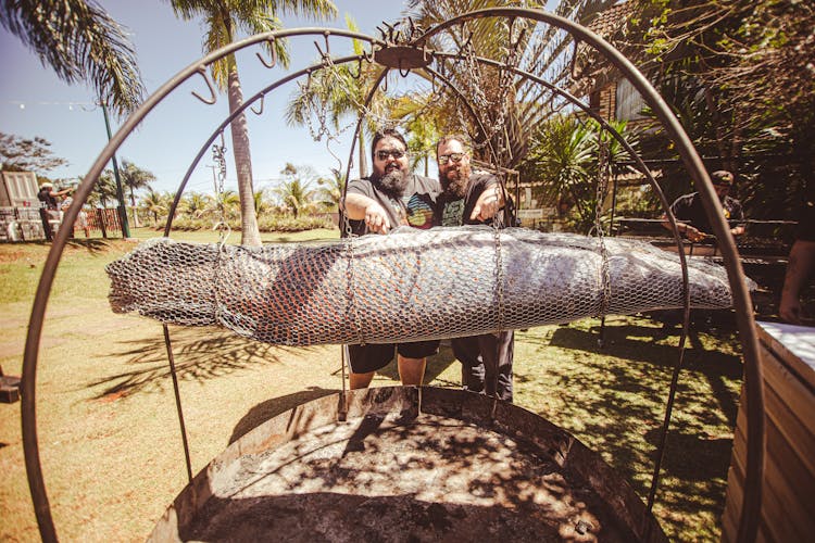 A Pair Of Bearded Men Grilling A Large Fish