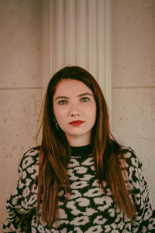 Free Portrait of a woman with red lips in leopard print sweater against column. Stock Photo
