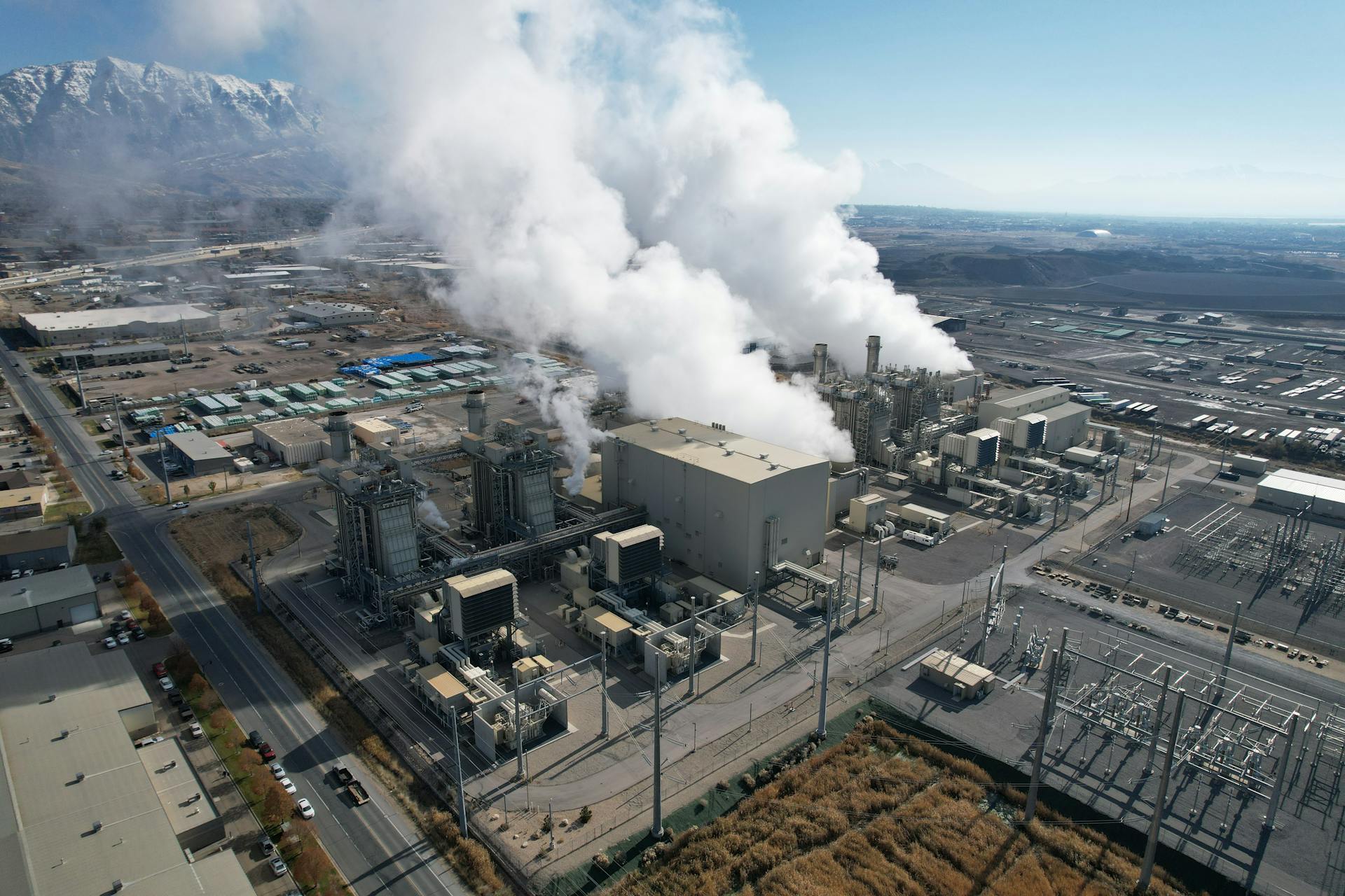 Aerial shot of an industrial plant emitting smoke in Lindon, Utah with mountains in the background.