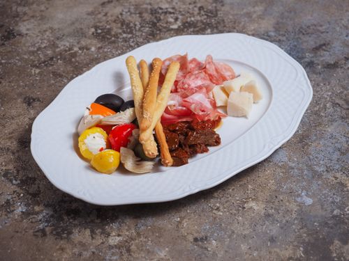Free A delicious Italian antipasti selection with breadsticks, meats, and cheeses on a white plate. Stock Photo