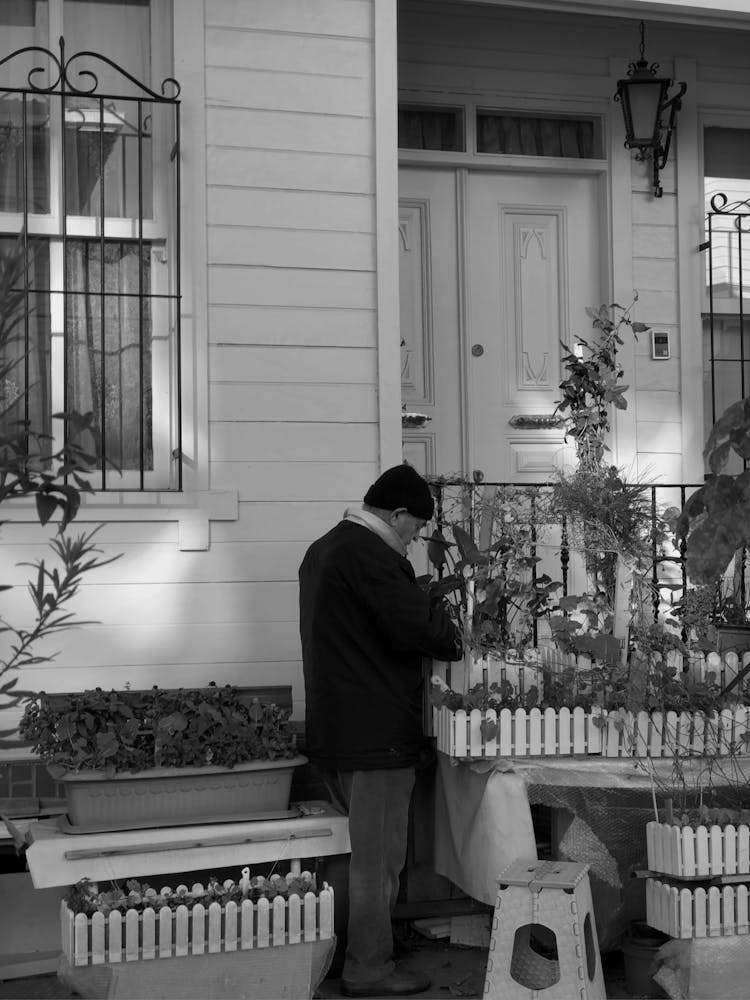 A Grayscale Of A Man In Winter Clothing Gardening