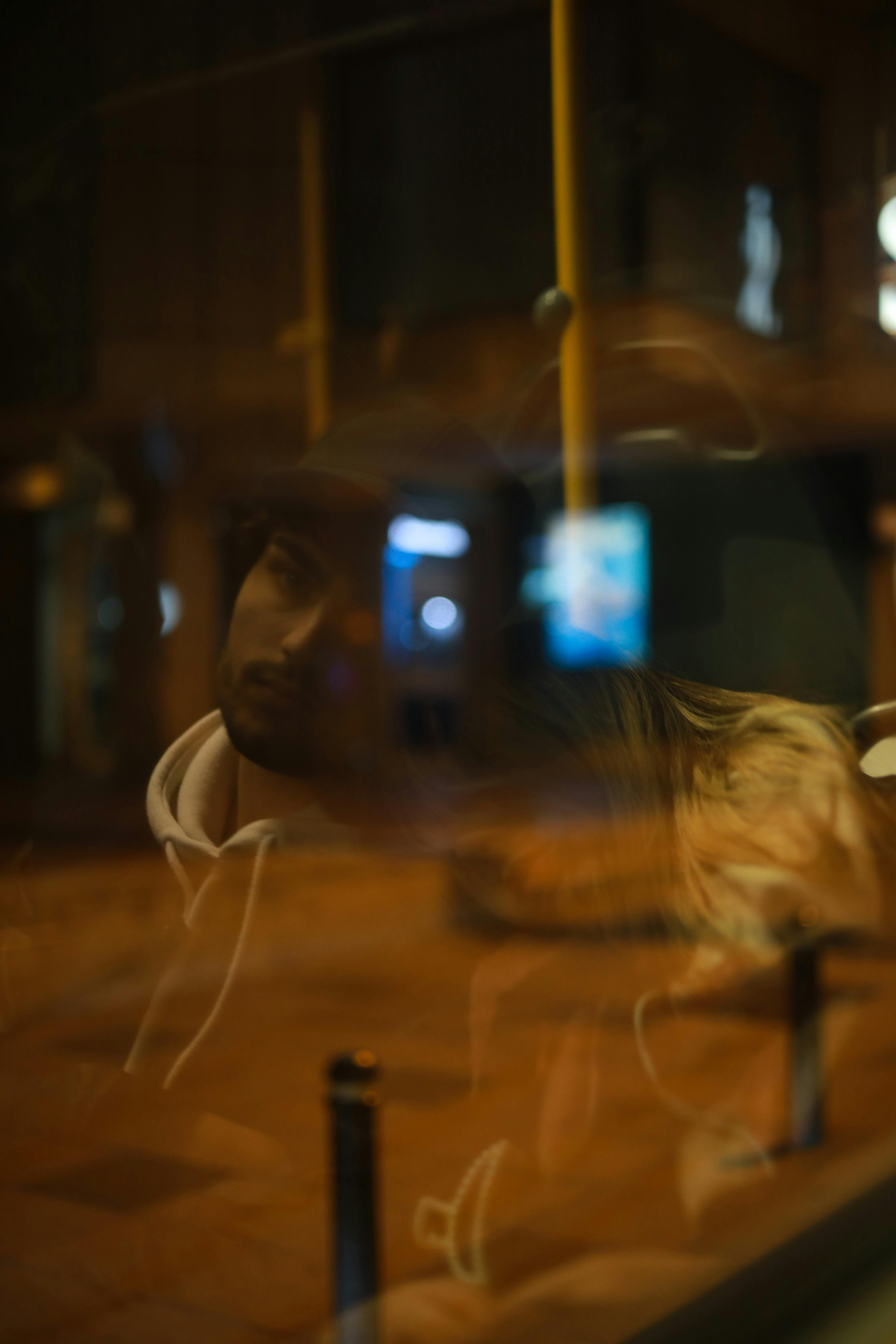 Blurred night shot of a couple reflected in bus window, capturing the city's essence.