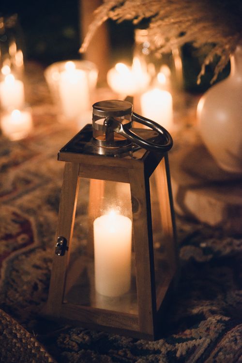 Free Warm ambient lighting with a lantern and candles on a patterned rug, perfect for cozy settings. Stock Photo