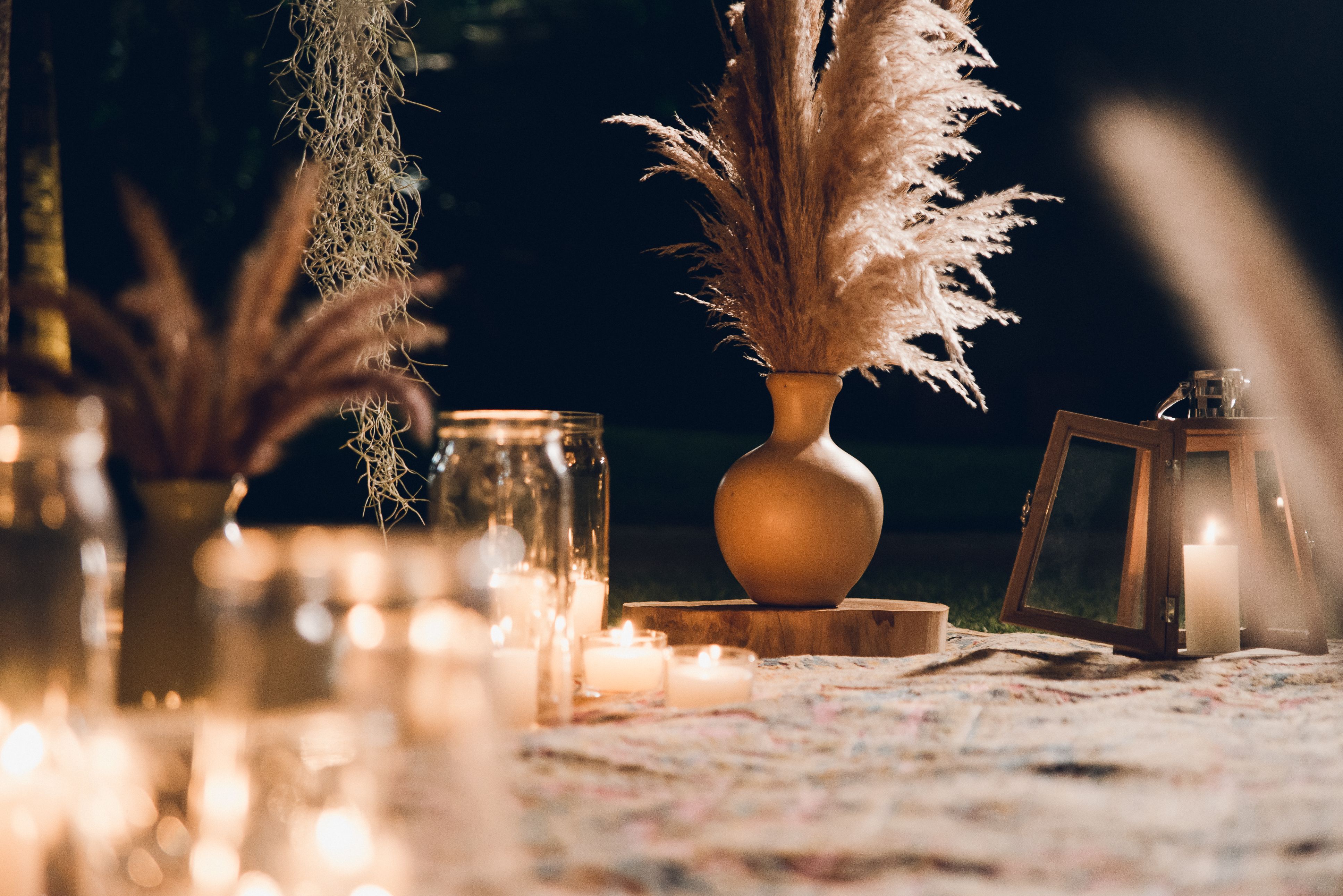 Cozy boho decor featuring candlelight and pampas grass in a vase for tranquil ambiance.