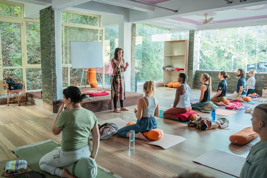 Yoga teacher leads a diverse group in a serene indoor studio setting in Rishikesh, India.