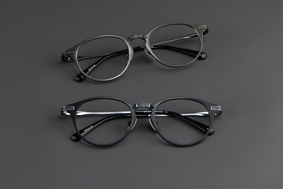 Close-up of two pairs of round black eyeglasses on a dark surface, highlighting modern eyewear style.