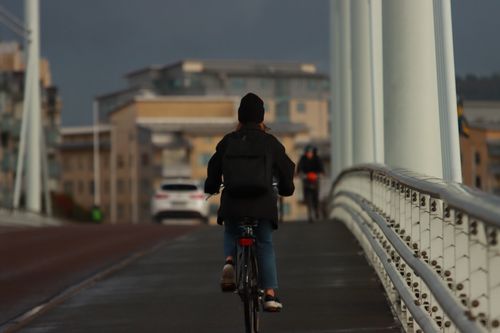 Free A woman cycling on a bridge in an urban setting, highlighting daily commutes. Stock Photo