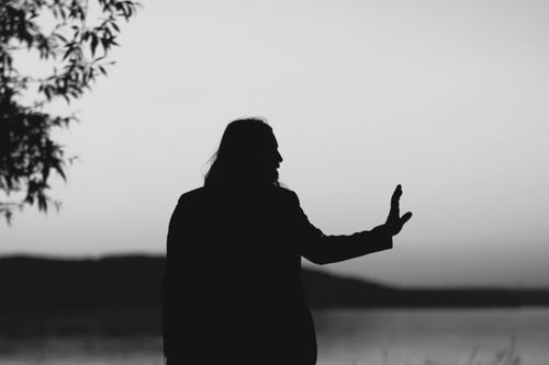 Free A monochrome image of a silhouetted man near water, conveying tranquility. Stock Photo