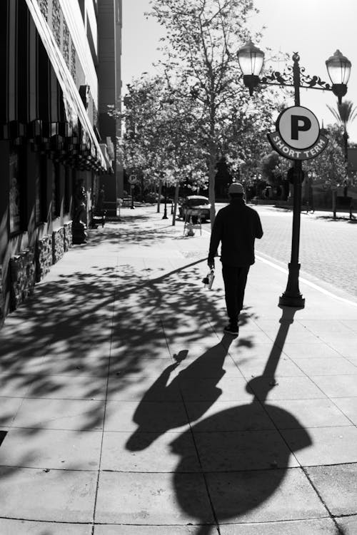 Free Grayscale Photo of a Person Walking on the Sidewalk Stock Photo