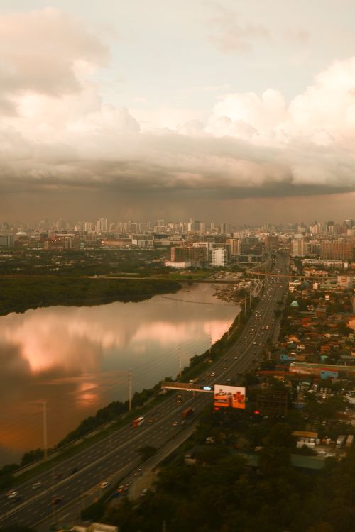 Free A stunning aerial view of a cityscape with a reflective river and dramatic sunset sky. Stock Photo