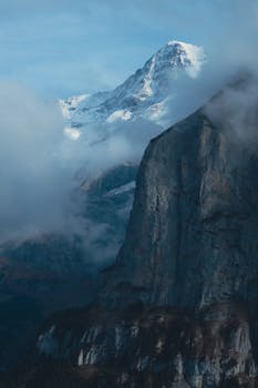 Breathtaking view of a snowcapped mountain peak shrouded in misty clouds.