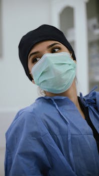Close-up of a female healthcare worker wearing a surgical mask and scrubs.