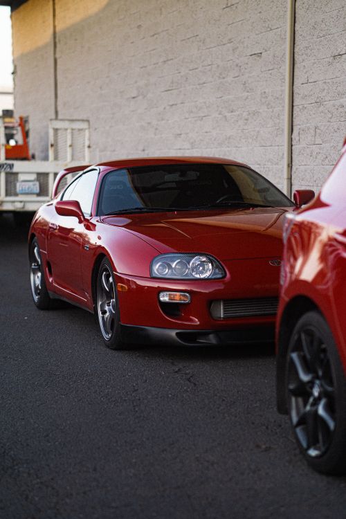 Free A sleek red sports car parked on an urban street, depicting modern automotive design. Stock Photo