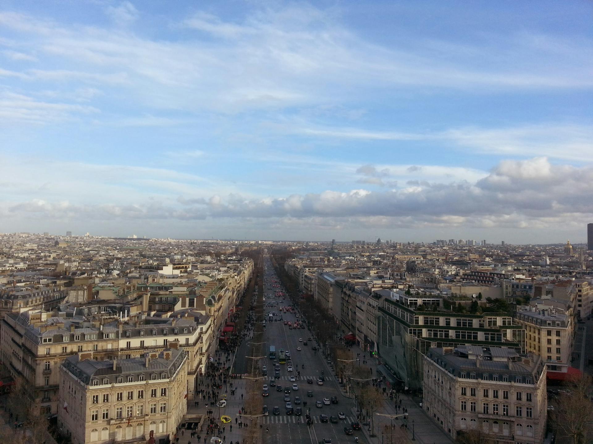 Breathtaking aerial view of Avenue des Champs-Élysées and Paris cityscape under a clear blue sky.