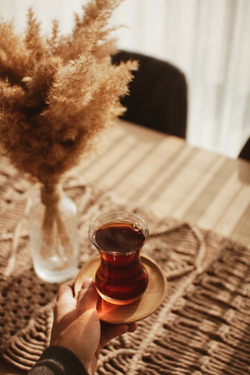 Man Holding a Cup of Tea over a Table 