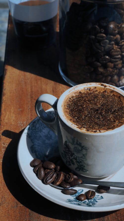 A Cup of Coffee on Ceramic Saucer with Coffee Beans