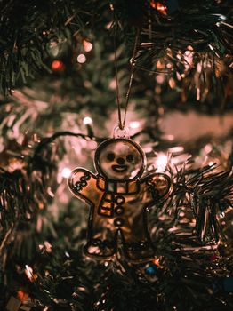 A cozy close-up of a gingerbread man ornament amid warm Christmas tree lights.