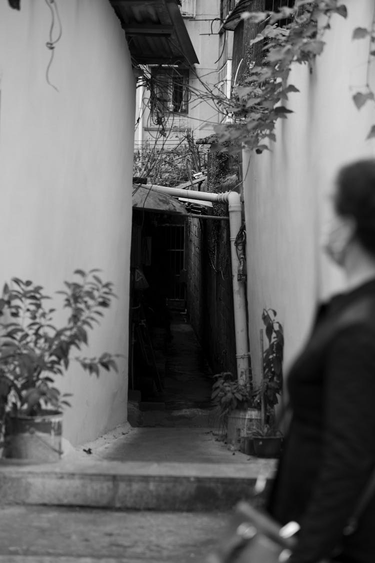 Grayscale Photo Of Woman In Black Shirt Standing Near Door