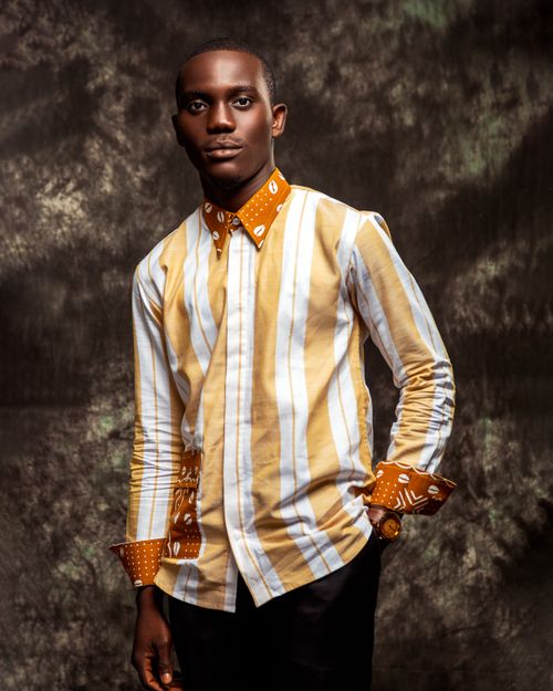 Free Elegant portrait of a stylish man in a striped long sleeve shirt against a textured backdrop. Stock Photo