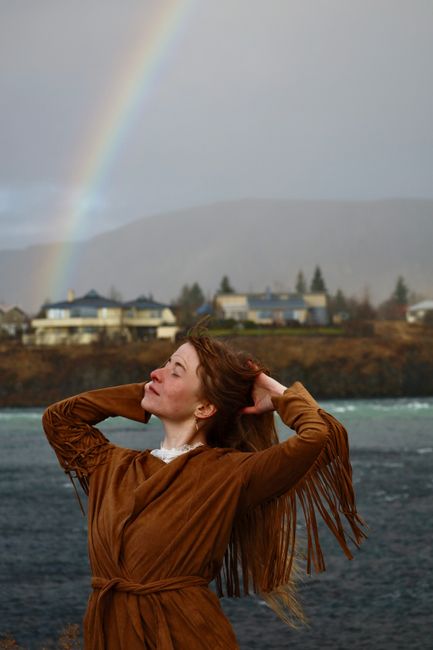 Portrait of a woman in Selfoss, Iceland, enjoying the outdoors with a rainbow in the background.