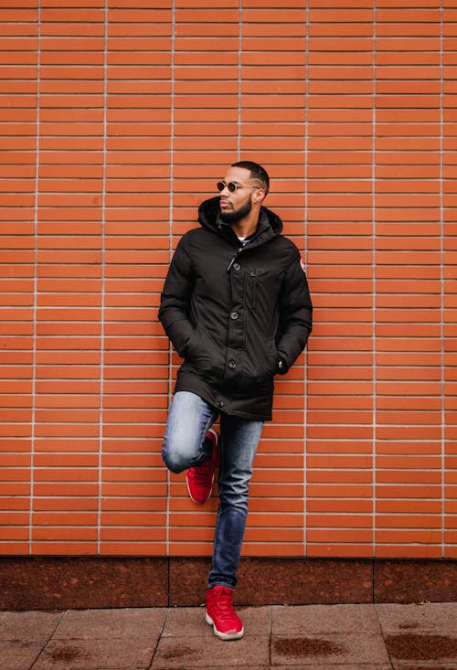 Young Man in a Black Coat and Jeans Standing with his Hands in Pockets 