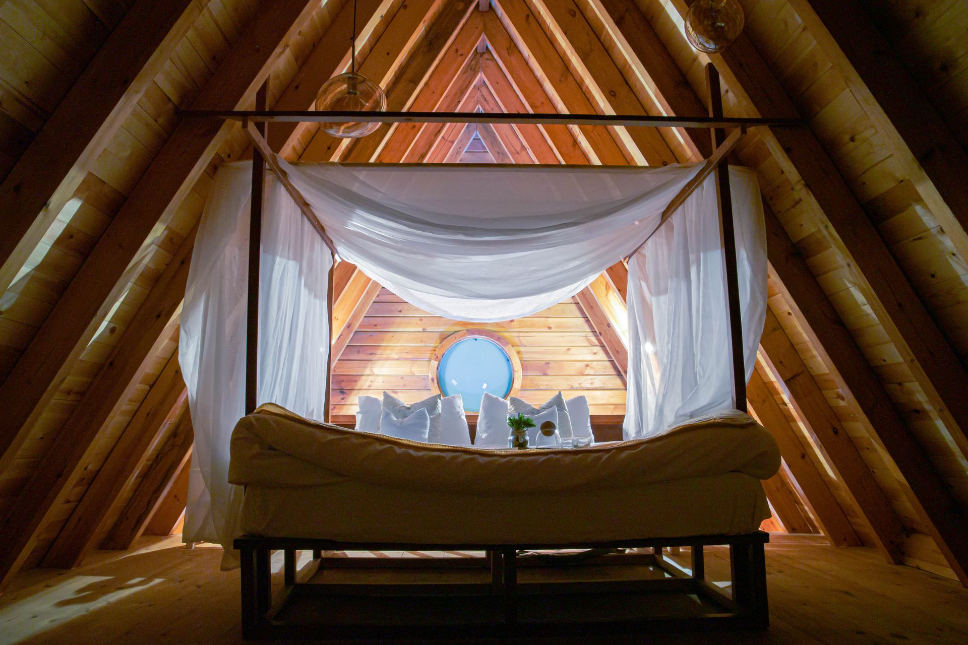 Elegant rustic attic bedroom with a canopy bed and wooden interior design.