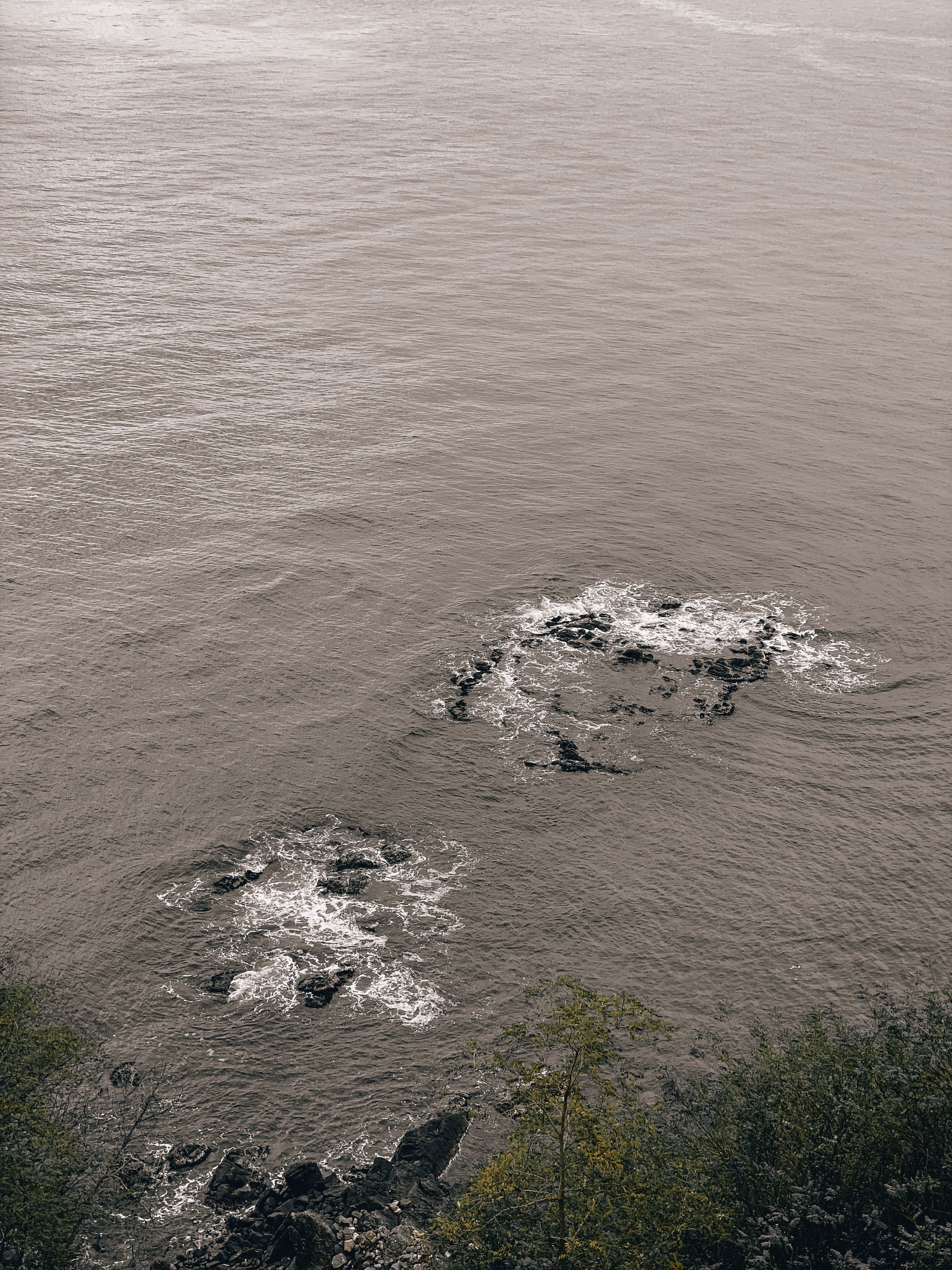 Black Rocks on Body of Water · Free Stock Photo