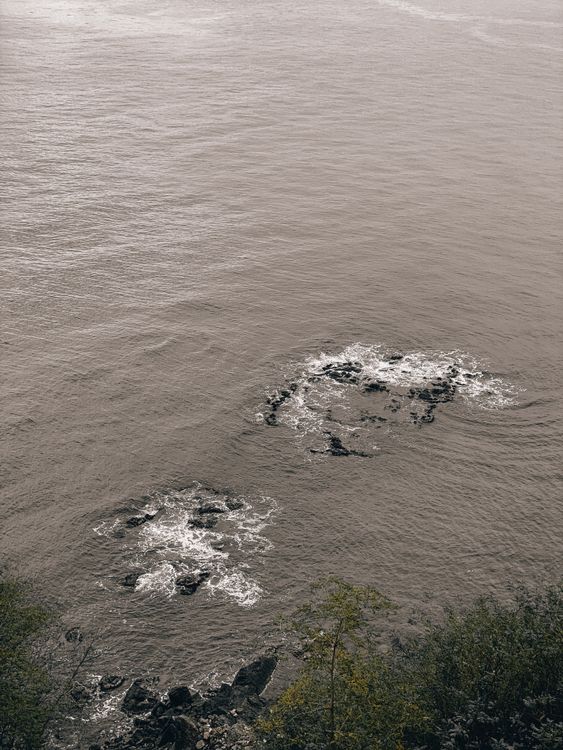 Black Rocks Underwater Black Rocks on Body of Water · Free Stock Photo