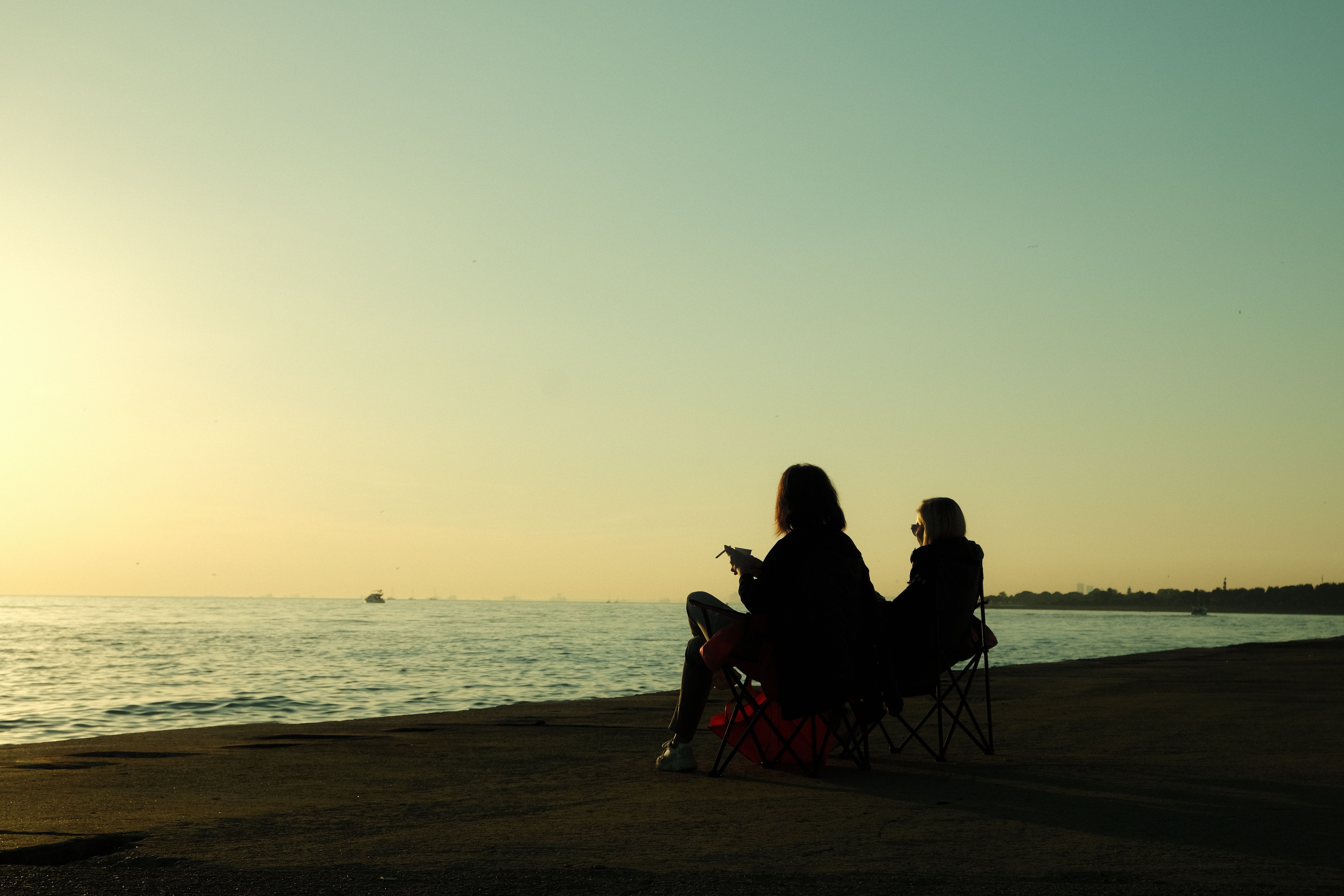 Silhouette of Two People Sitting on the Beach during Sunset · Free ...