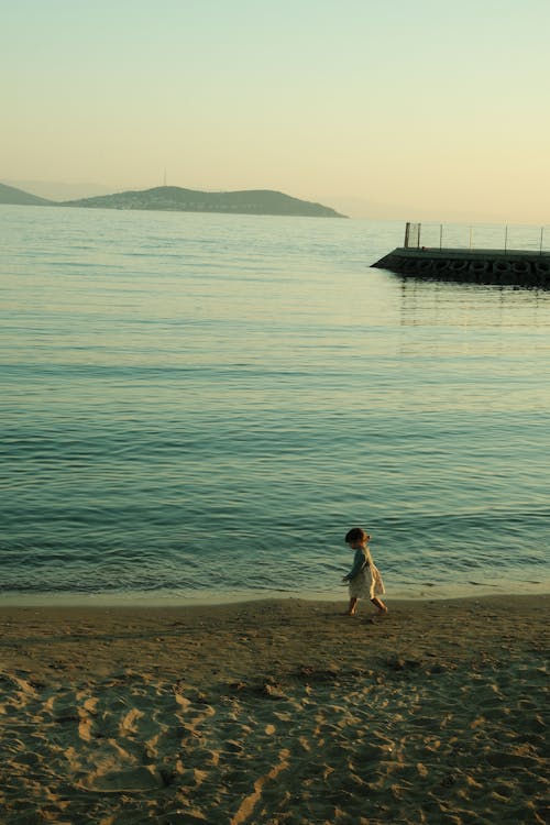 A Child Walking on a Beach at Sunset