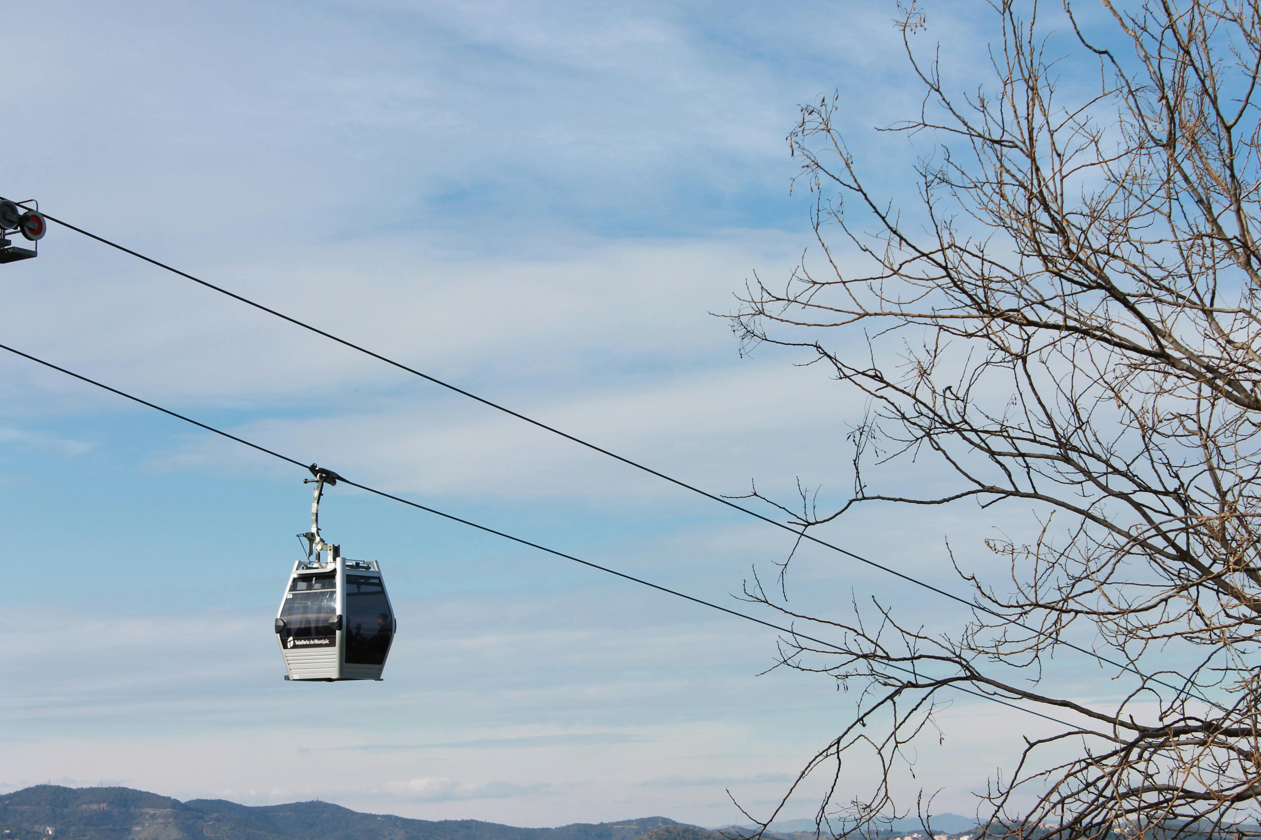 Free A scenic view of a cable car traveling against a clear blue sky and bare tree branches. Stock Photo