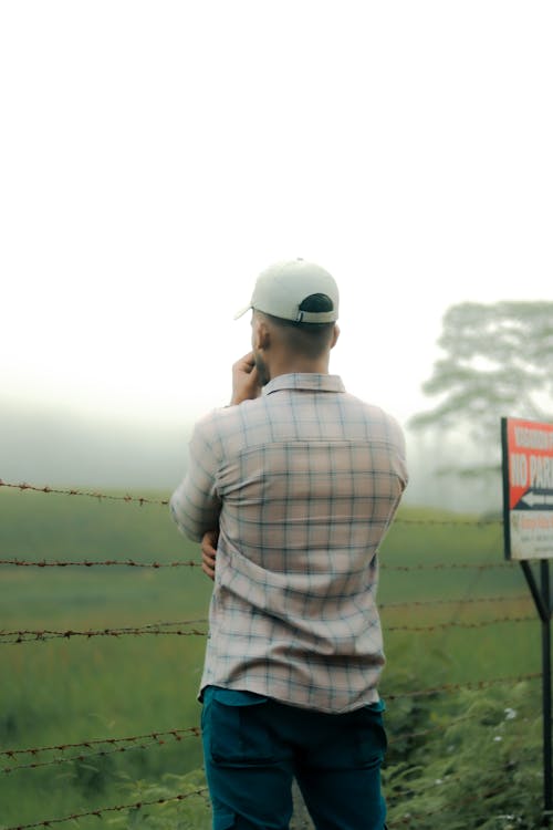 Man Standing behind a Barbed Wire Fence and Looking at a View 