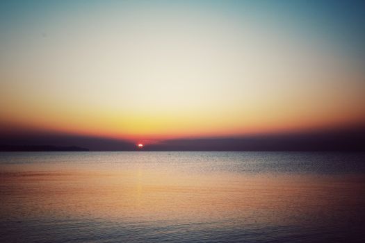 A peaceful sunrise over the ocean with a colorful twilight sky reflecting on calm waters.