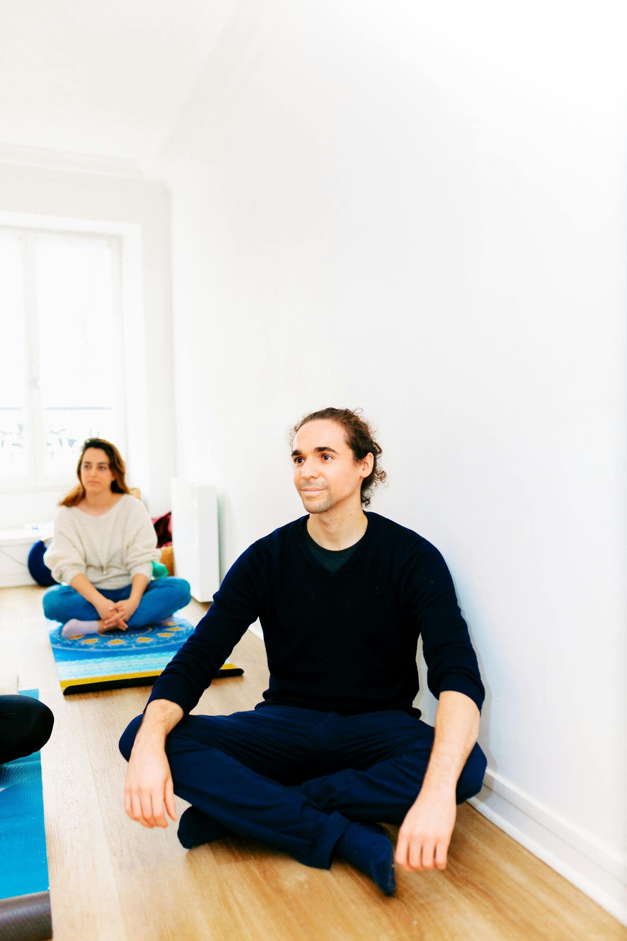 People practicing yoga and meditation in a bright indoor space, promoting relaxation and mindfulness.