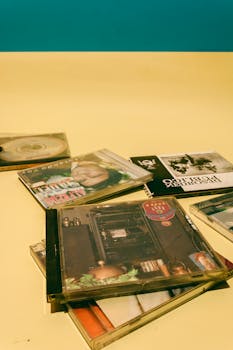 Stylish flat lay of various music CD covers on vibrant yellow surface.