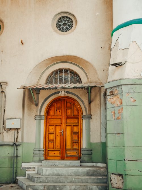 Free A vintage wooden door with an archway and steps in an urban setting, offering a glimpse into classic architecture. Stock Photo