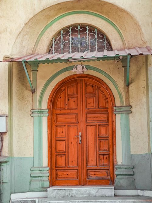 Free A vintage wooden door set in an elegant archway with detailed design elements. Stock Photo