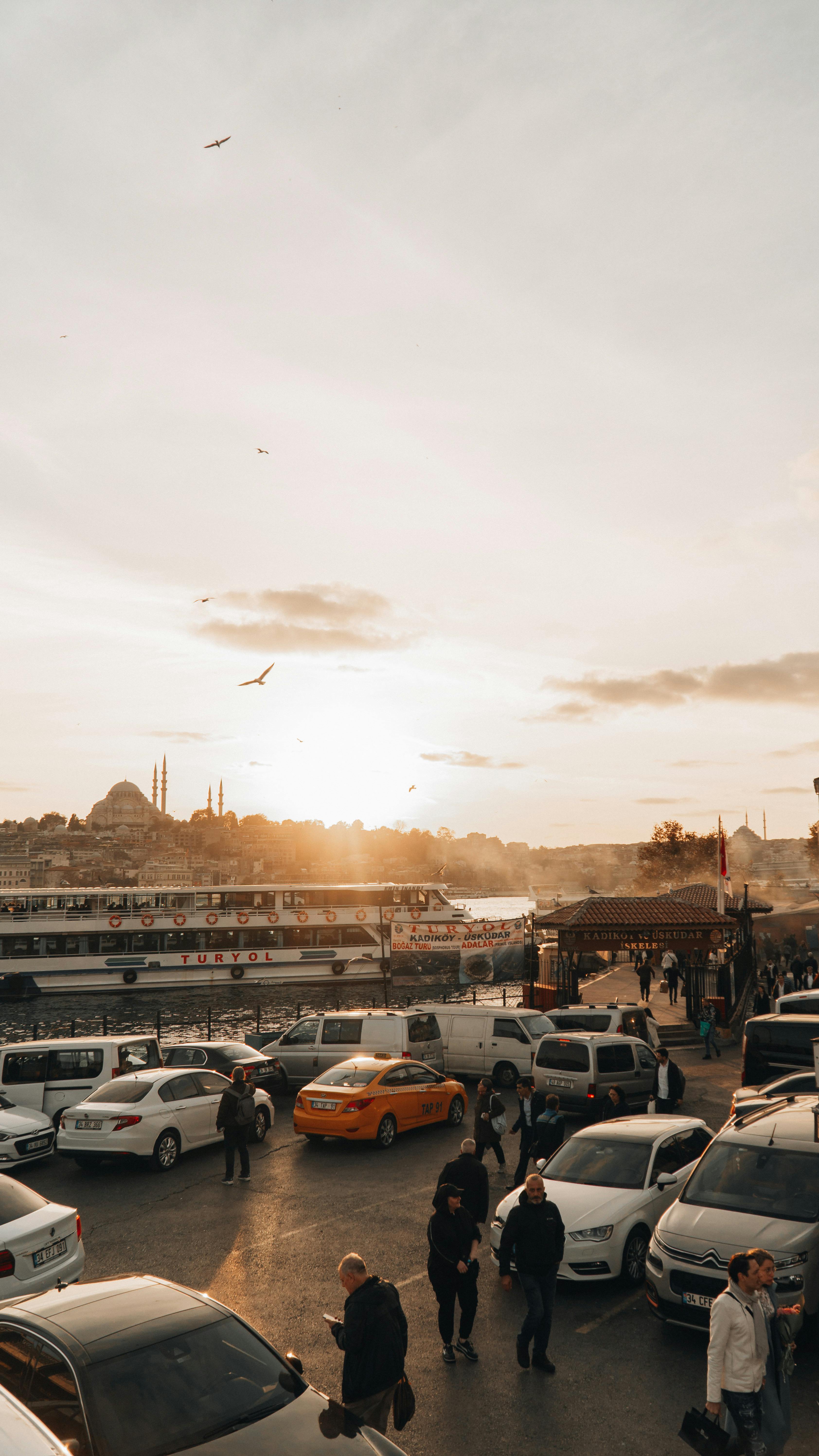 A vibrant evening scene in Istanbul featuring bustling streets, parked cars, and the iconic Bosphorus skyline.