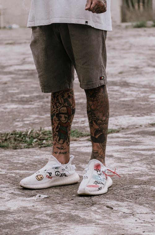 A Tattooed Person in Gray Shorts Standing on the Street