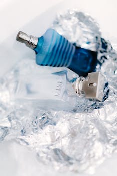 Close-up of stylish blue and clear perfume bottles displayed on a reflective surface.